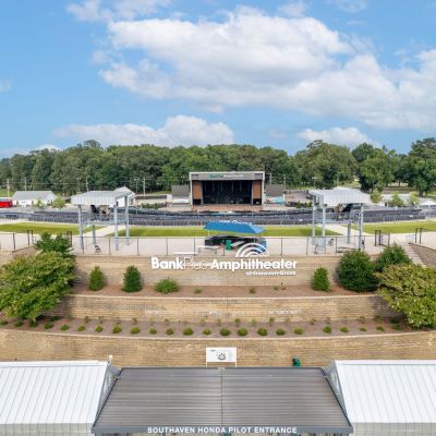 High-angle view of the BankPlus Amphitheater at Snowden Grove in Southaven, Mississippi, highlighting the open-air pavilion stage, seating bowl, and terraced stone entry walls