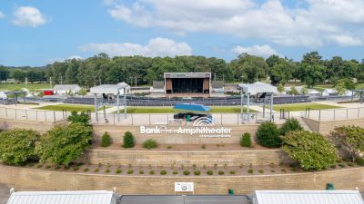 High-angle view of the BankPlus Amphitheater at Snowden Grove in Southaven, Mississippi, highlighting the open-air pavilion stage, seating bowl, and terraced stone entry walls