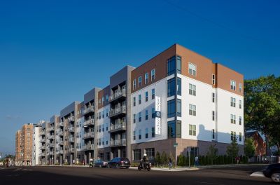 Exterior street view of Madison McLean, a modern five-story Memphis apartments complex with mixed materials, private balconies, and ground-floor retail
