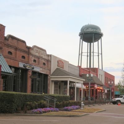 Historic downtown Collierville town square near Memphis featuring brick storefronts, boutique shops, street lamps, and the landmark Collierville water tower