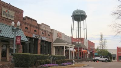 Historic downtown Collierville town square near Memphis featuring brick storefronts, boutique shops, street lamps, and the landmark Collierville water tower