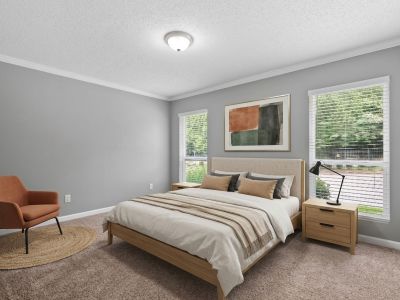 Virtually staged bedroom with grey walls, a light wood bed frame, terracotta accents, and an armchair at Annie's Townhomes and Apartments in Memphis.