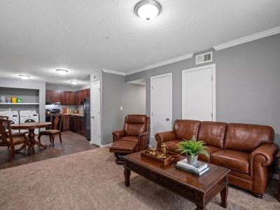 Open-concept apartment floor plan with a brown leather sofa, a dining table, and an adjacent kitchen with laundry units at Annie's Townhomes and Apartments in Memphis.