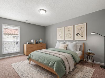 Staged bedroom featuring a sage green duvet, minimalist line art decor, a light wood dresser, and a large window at Annie's Townhomes and Apartments in Memphis