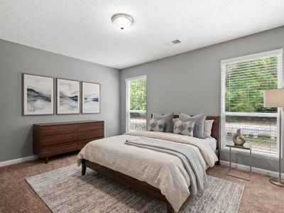 Modern staged bedroom with a dark wood bed frame and matching dresser, neutral bedding, and scenic wall art at Annie's Townhomes and Apartments in Memphis.