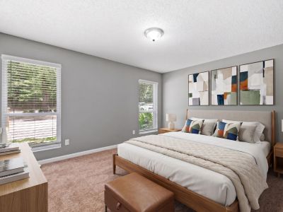 Staged bedroom featuring a mid-century modern wooden bed frame, geometric wall decor, and large windows providing natural light at Annie's Townhomes and Apartments in Memphis