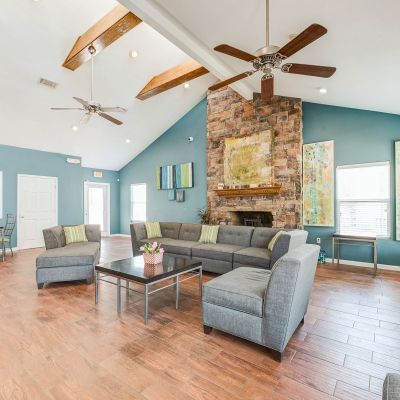Clubhouse lounge with vaulted ceilings, a stone fireplace, and teal walls at Annie's Townhomes and Apartments in Memphis.