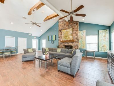 Clubhouse lounge with vaulted ceilings, a stone fireplace, and teal walls at Annie's Townhomes and Apartments in Memphis.
