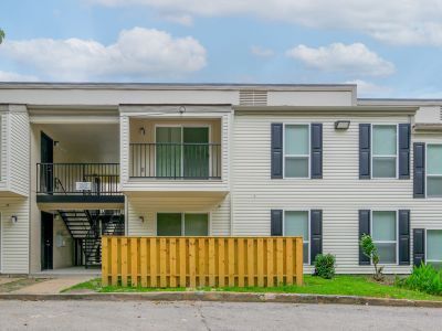 Tan two-story apartment exterior with black shutters and a wooden fence at Annie's Townhomes and Apartments in Memphis