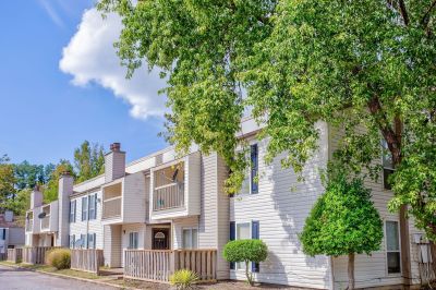 Exterior view of the two-story traditional siding townhome buildings framed by lush green trees at Annie's Townhomes and Apartments in Memphis.