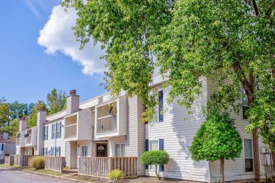 Exterior view of the two-story traditional siding townhome buildings framed by lush green trees at Annie's Townhomes and Apartments in Memphis.