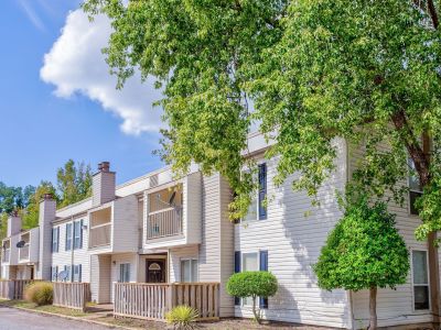 Exterior view of the two-story traditional siding townhome buildings framed by lush green trees at Annie's Townhomes and Apartments in Memphis.