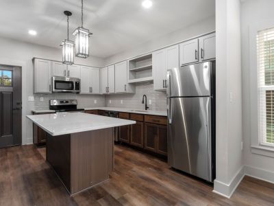 Renovated Memphis apartments kitchen at The Park featuring a center island with quartz countertop, two-tone cabinetry, subway tile backsplash, stainless steel appliances, and hardwood floors