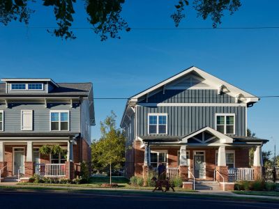 Two craftsman-style Memphis apartments buildings with brick bases, gray siding, covered front porches, and a resident walking a dog along the sidewalk