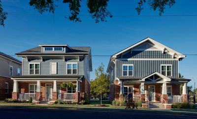 Two craftsman-style Memphis apartments buildings with brick bases, gray siding, covered front porches, and a resident walking a dog along the sidewalk