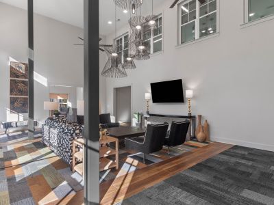 Upscale resident clubhouse lounge at The Park Memphis apartments with double-height ceilings, sculptural pendant lighting, patterned seating, and wall-mounted TV