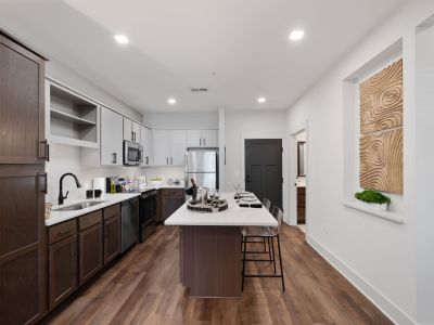 Modern Memphis apartments kitchen at The Park with two-tone dark and gray cabinetry, quartz island with bar seating, subway tile backsplash, and stainless steel appliances