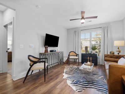 Furnished living room in a Memphis apartments unit at The Park featuring hardwood floors, ceiling fan, wall-mounted TV, and sliding glass door leading to natural light