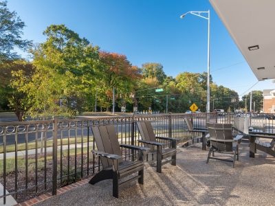 Outdoor resident lounge patio at The Park Memphis apartments on Sam Cooper Boulevard, with Adirondack chairs, decorative iron railing, and views of tree-lined streets
