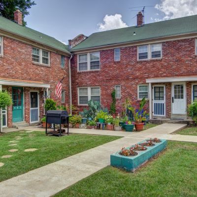 Charming brick courtyard area with individual apartment entry doors, potted plants, and a barbecue grill at Audubon Downs apartments in Memphis.