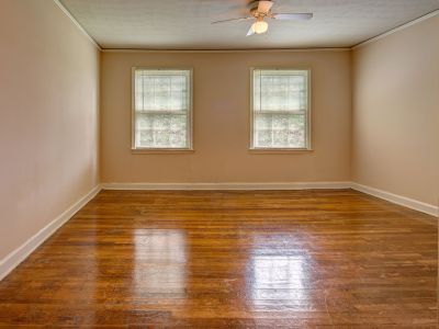 Empty room highlighting polished hardwood flooring and dual windows at Audubon Downs apartments in Memphis