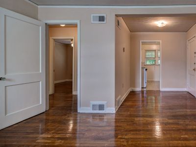 Spacious apartment interior featuring glossy hardwood floors and open doorways at Audubon Downs apartments in Memphis.