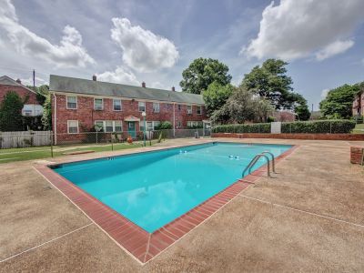 Gated community swimming pool backed by two-story brick residences at Audubon Downs apartments in Memphis.