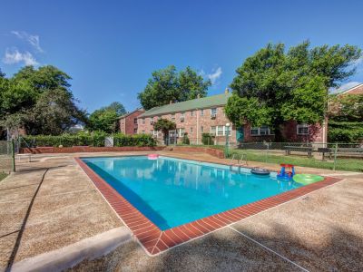 Clear blue swimming pool with colorful pool floats on a sunny day at Audubon Downs apartments in Memphis.