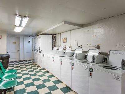 On-site community laundry facility equipped with multiple washers, dryers, and green plastic seating at Audubon Downs apartments in Memphis