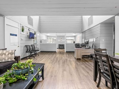 Main clubhouse and leasing office interior featuring a resident lounge area, workspace desks, and grey wood-paneled walls at The Birches Townhomes in South Memphis.