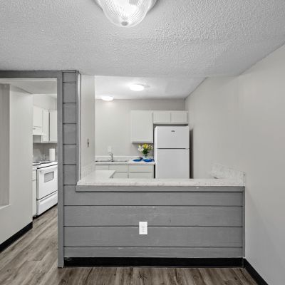 Dining area view looking past a grey wood breakfast bar wall into the kitchen with wood-look flooring at The Birches Townhomes in South Memphis.