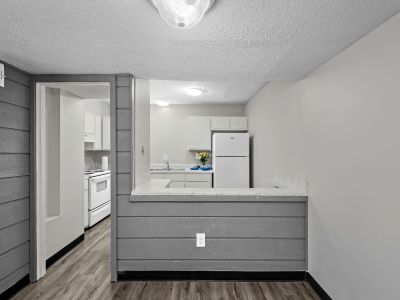 Dining area view looking past a grey wood breakfast bar wall into the kitchen with wood-look flooring at The Birches Townhomes in South Memphis.