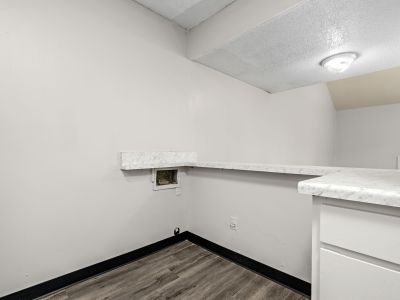 In-unit laundry utility nook equipped with washer and dryer hookups, a marble-patterned folding shelf, and vinyl flooring at The Birches Townhomes in South Memphis.