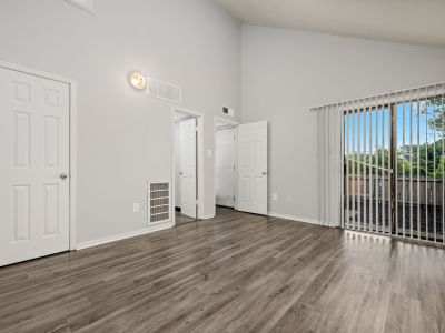 Empty townhome room showing multiple interior closet doors and a sliding glass door with vertical blinds leading outside at The Birches Townhomes in South Memphis.