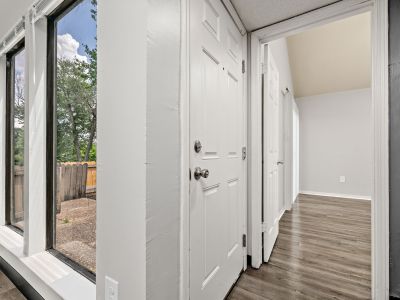 Interior perspective from a doorway showing large floor-to-ceiling windows and wood-style flooring transitioning into an adjacent room at The Birches Townhomes in South Memphis.