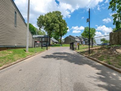 Entrance driveway into the community featuring an open black security gate and surrounding townhome buildings at The Birches Townhomes in South Memphis.