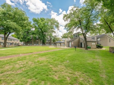 Wide-angle perspective of a massive open green courtyard lawn with a concrete walkway leading toward a distant gazebo at The Birches Townhomes in South Memphis.