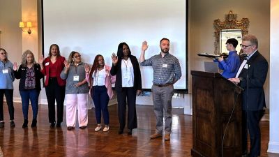 Property management professionals raising their right hands during an official induction ceremony at a business event.