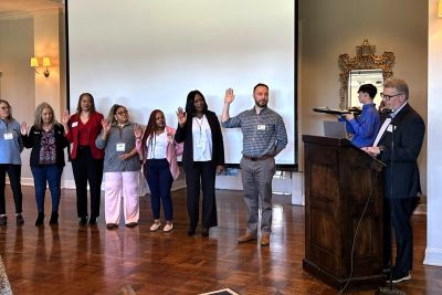Property management professionals raising their right hands during an official induction ceremony at a business event.