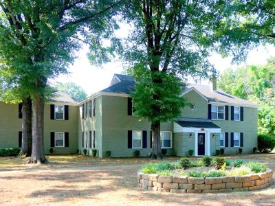 Lush green lawn and mature trees surrounding a stone retaining wall at Bluff City Apartments in Memphis.
