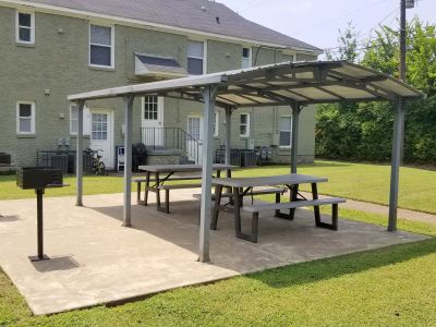 Covered outdoor picnic pavilion with tables and charcoal grills at Bluff City Apartments in Memphis.