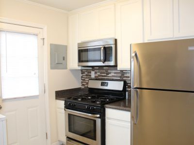 Modern kitchen with white cabinetry, stainless steel appliances, and a mosaic tile backsplash at Bluff City Apartments in Memphis.