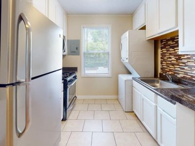 Galley kitchen with tile floors, white cabinets, stainless steel appliances, and a stacked washer and dryer at Bluff City Apartments in Memphis