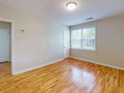 Spacious empty room with pristine hardwood flooring, neutral paint, and a large window view at Bluff City Apartments in Memphis.