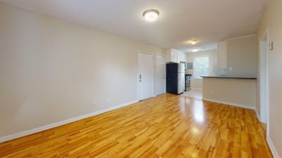 Open concept living room featuring polished hardwood flooring that flows into a kitchen layout at Bluff City Apartments in Memphis.