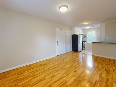 Open concept living room featuring polished hardwood flooring that flows into a kitchen layout at Bluff City Apartments in Memphis.