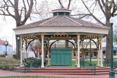 Scenic view of a large covered wooden community gazebo adorned with warm string lights, located in a park area with mature trees—highlighting Collierville's local civic charm.