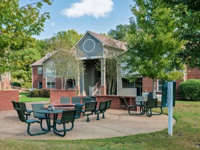Outdoor resident courtyard and brick fire pit area with green metal picnic tables at Champion Hills apartments in Memphis