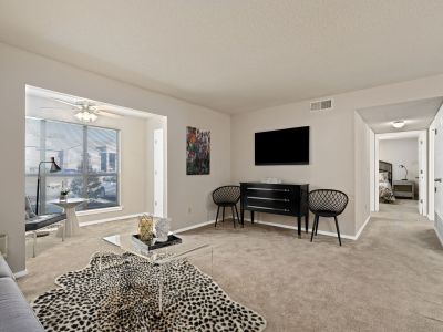 Modern apartment living room interior featuring neutral walls, a wall-mounted TV, and a stylized animal-print rug at Champion Hills in Memphis
