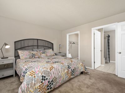 Spacious apartment bedroom featuring a large bed with a patterned comforter, adjacent walk-in closet, and ensuite bathroom at Champion Hills in Memphis.